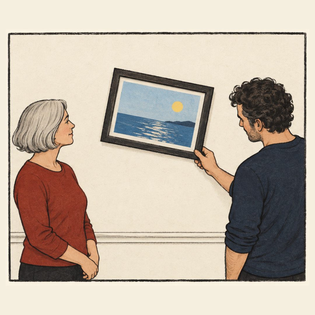 The woman has lowered her hands. The man holds the frame’s lower-right corner, tilting the seascape clockwise while the wall molding stays level. Both look calm.